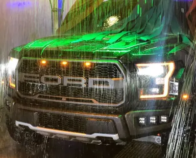 Ford Raptor under green-lit rinse water inside the tunnel