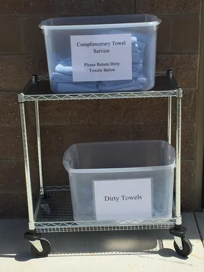 Complimentary towel cart with clean towels on top and a dirty towel bin below