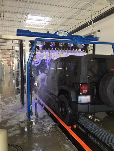 Black Jeep moving under a foam arch inside the wash tunnel