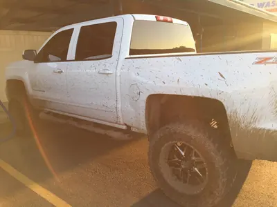 White Silverado pickup splattered with red mud before its wash