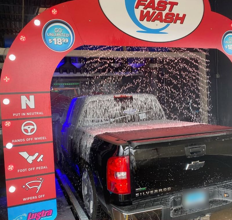 Black Chevy Silverado covered in foam as it enters under the red Fast Wash arch