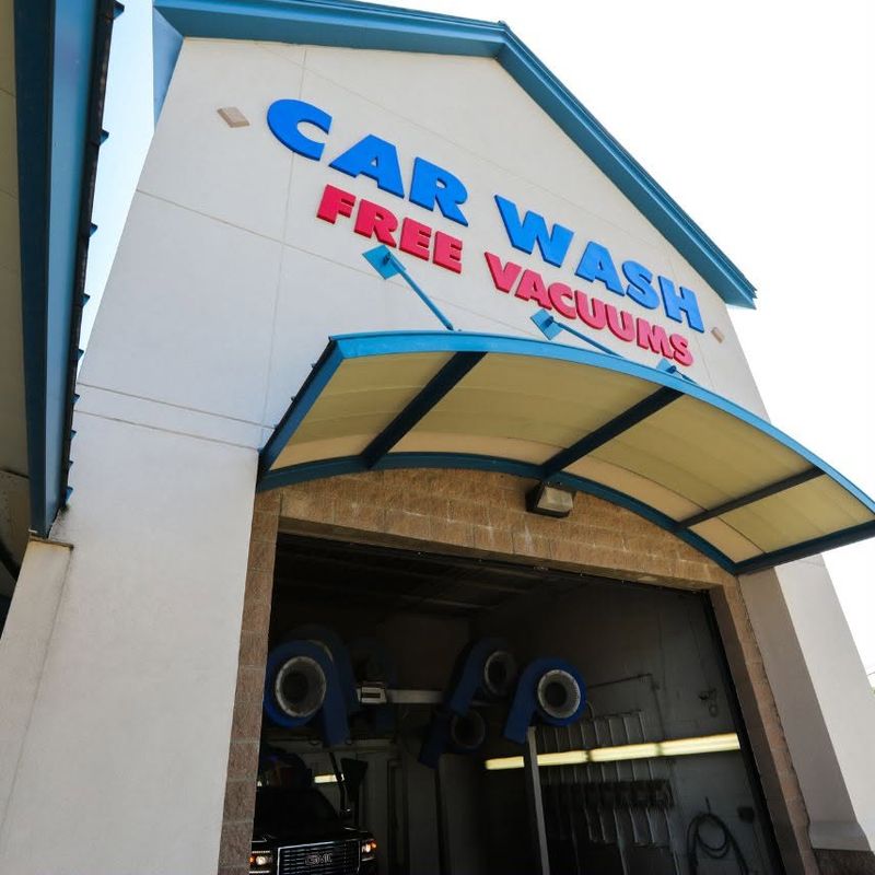 Fast Wash Coweta tunnel entrance under the CAR WASH and FREE VACUUMS sign